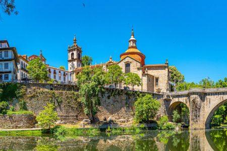 Panoramic view of Amarante, Portugal with the historic São Gonçalo Church and stone bridge reflected in the Tâmega River on a sunny day